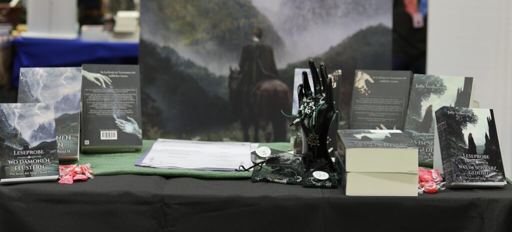 Bild von einem Messestand mit Büchern und Dekoration in dunklem Grün und Schwarz.